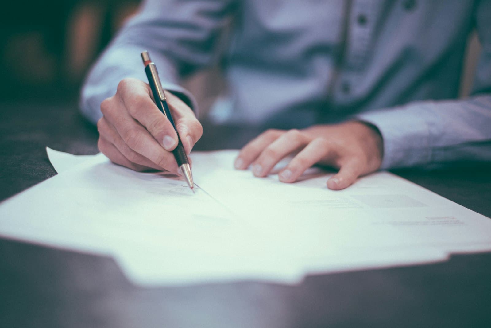 Person unterschreibt ein Dokument mit Stift